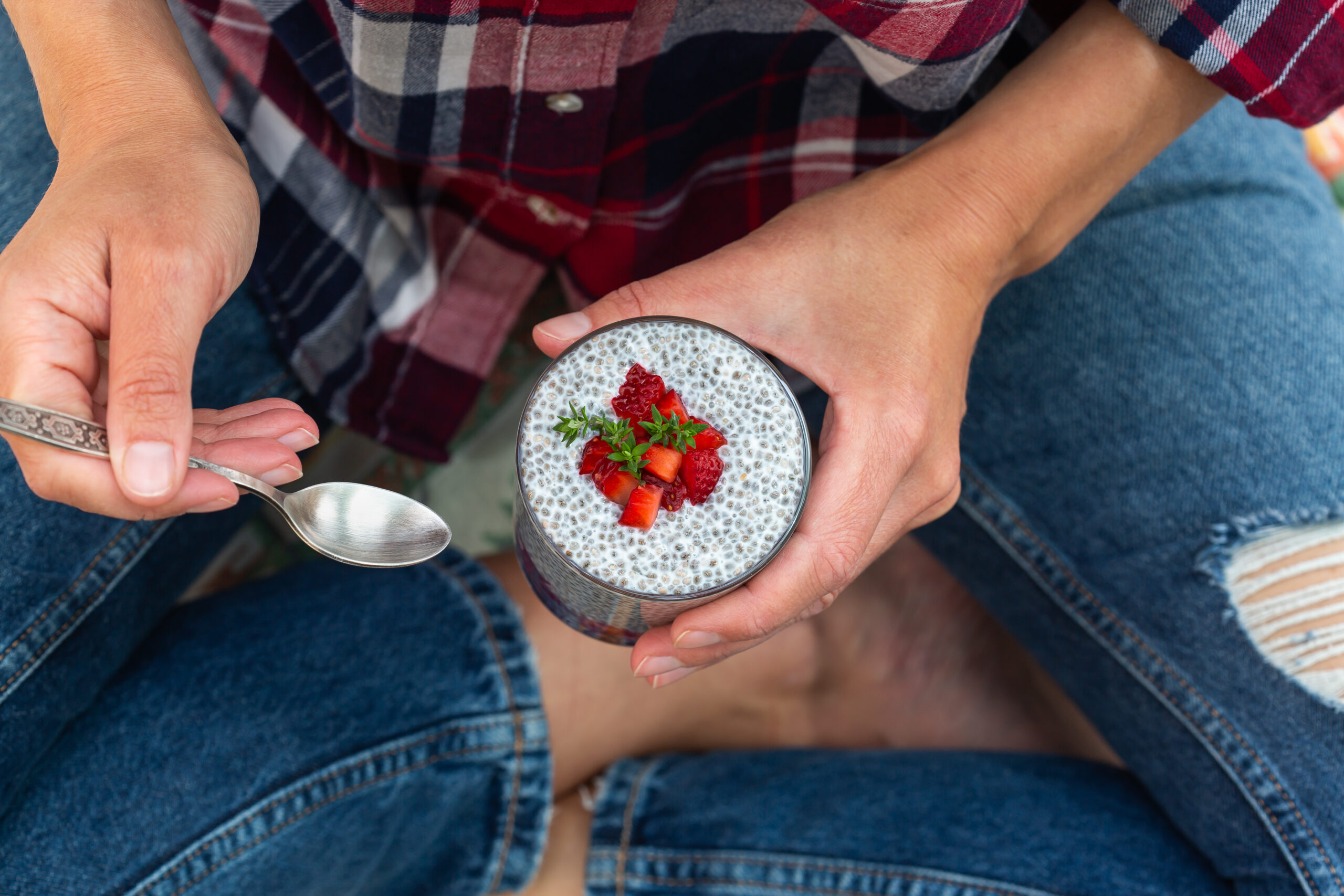 Vegan healthy eating and dieting food concept. Female hands holding chia pudding with fresh strawberries for breakfast